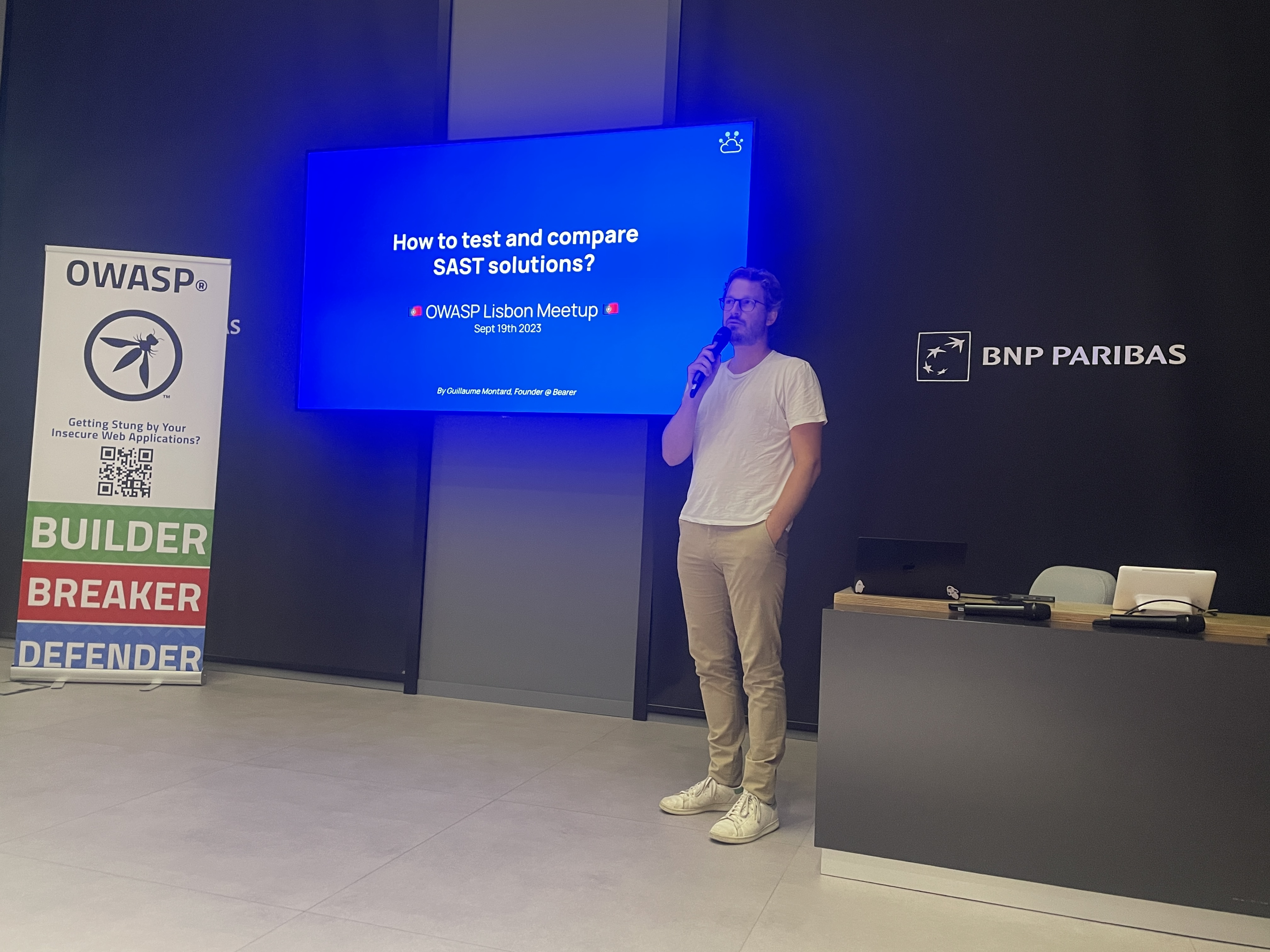 OWASP Lisboa #4 A speaker presenting a slide titled "How to test and compare SAST solutions?" while holding a microphone.