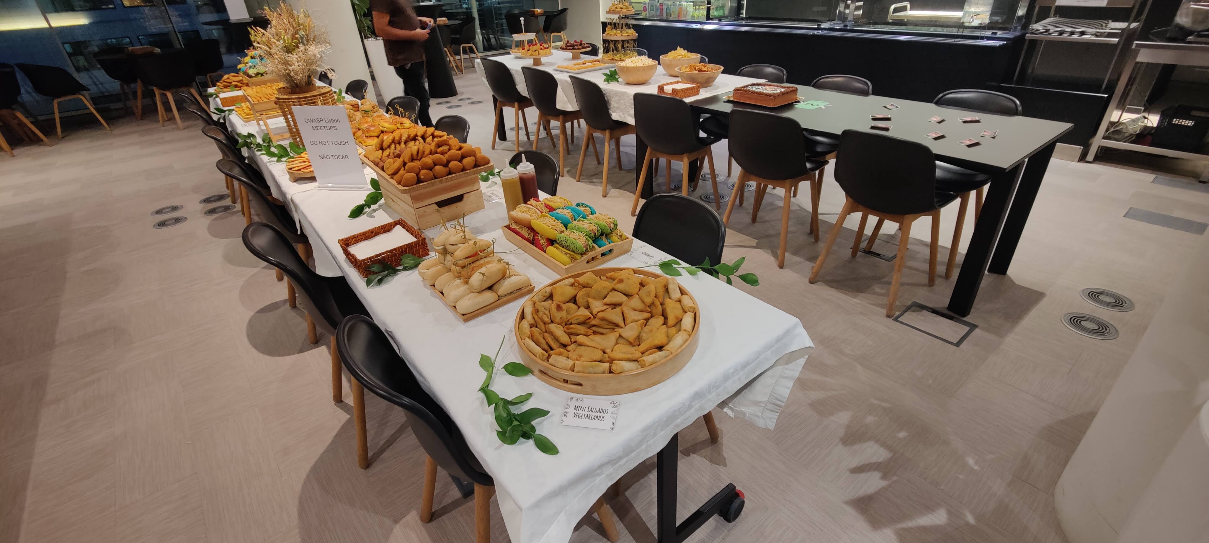 OWASP Lisboa #5 A buffet table loaded with savory snacks like samosas and sandwiches, with a "Do Not Touch" sign visible before the event starts.