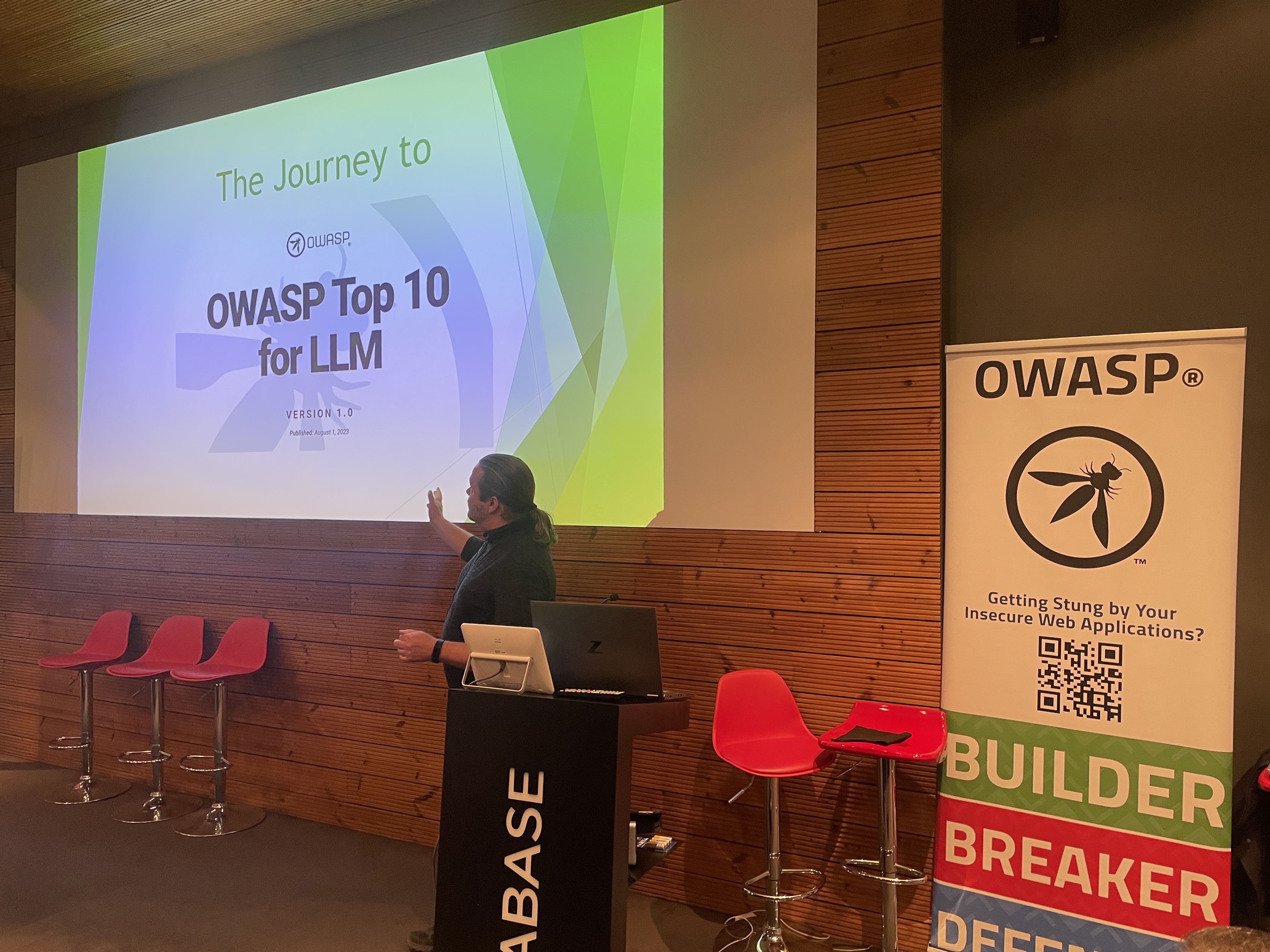 OWASP Lisboa #6 A speaker presenting a slide titled "The Journey to OWASP Top 10 for LLM" next to a vertical OWASP banner.