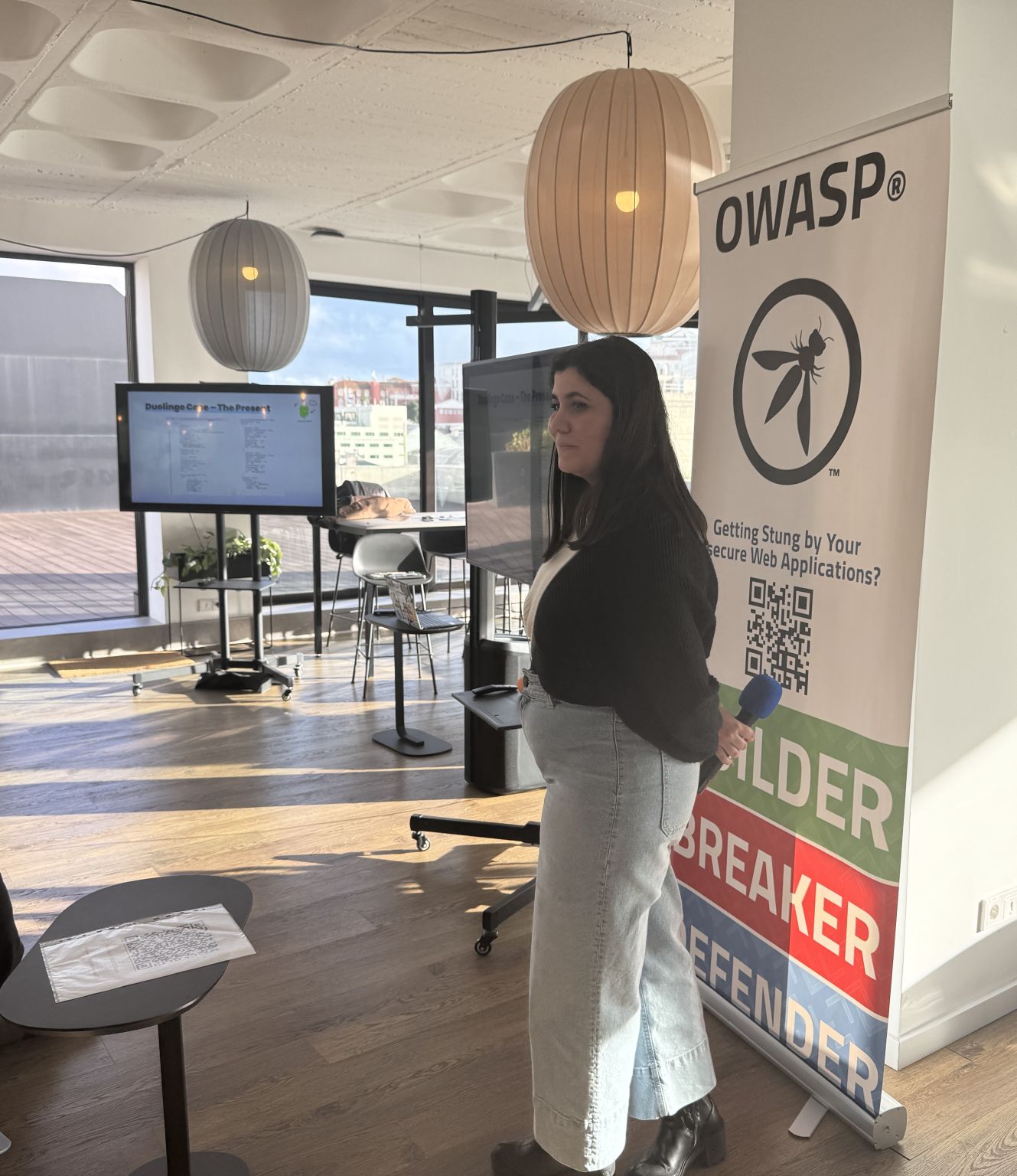 OWASP Lisboa #9 A speaker holding a microphone stands next to an OWASP banner, presenting a slide titled "Duolingo Case - The Present."