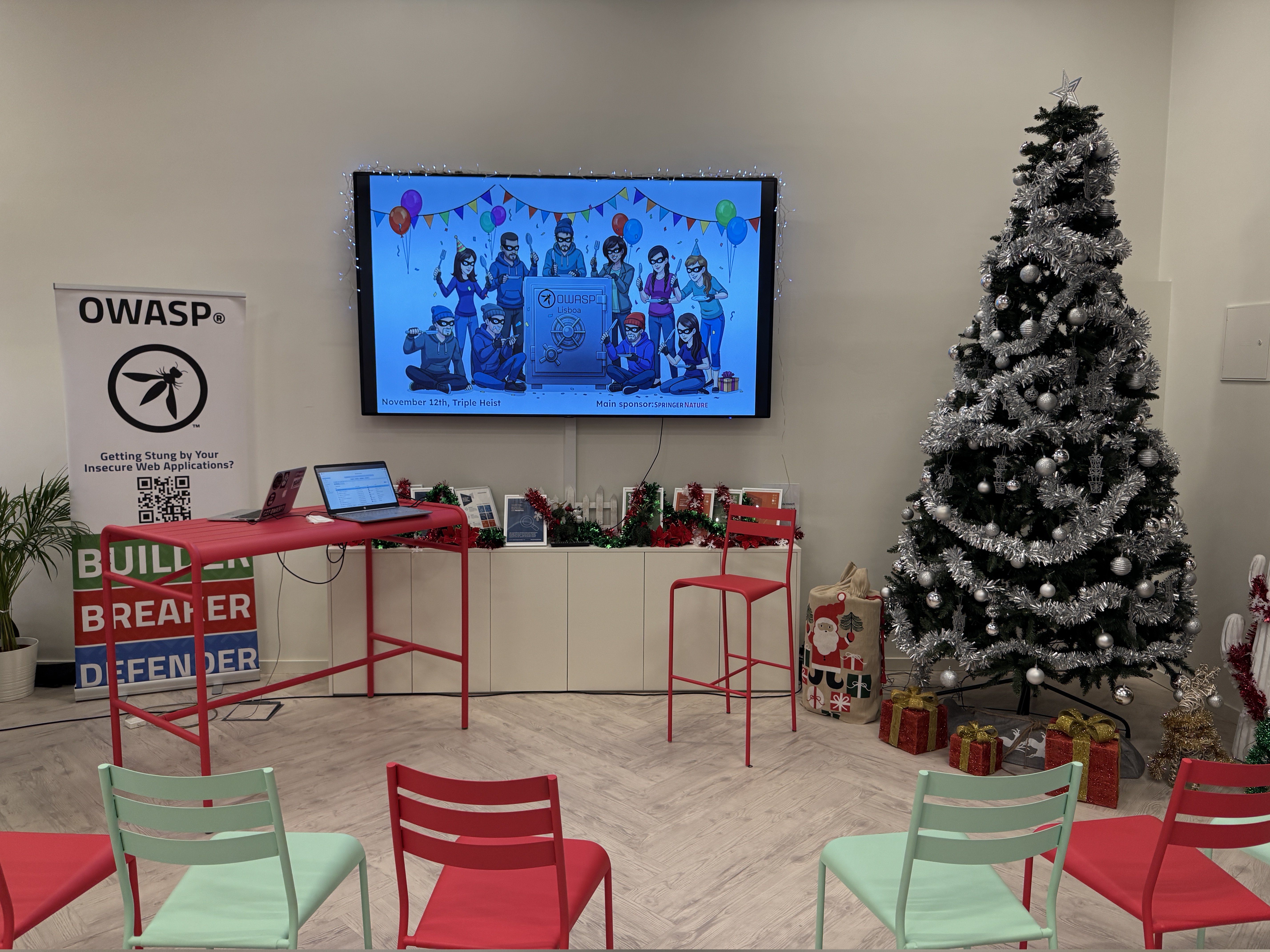 OWASP Lisboa #11 A festive setup featuring a Christmas tree and a screen displaying the "Triple Heist" event illustration with cartoon thieves and the date November 12th.