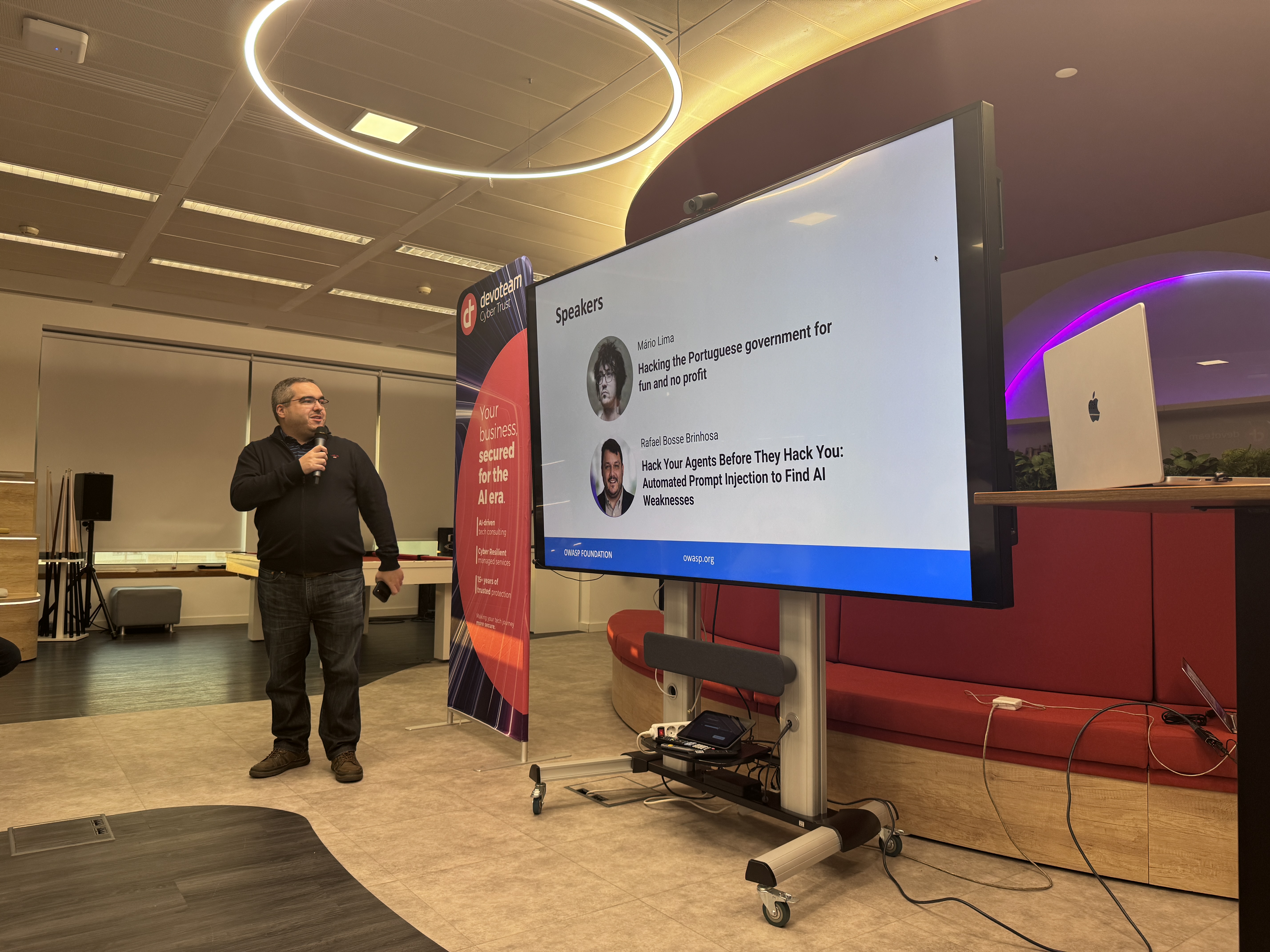 OWASP Lisboa #12 A digital display at the OWASP Lisboa event listing speakers Mário Lima and Rafael Bosse Brinhosa, with a Devoteam "Cyber Trust" banner in the background.