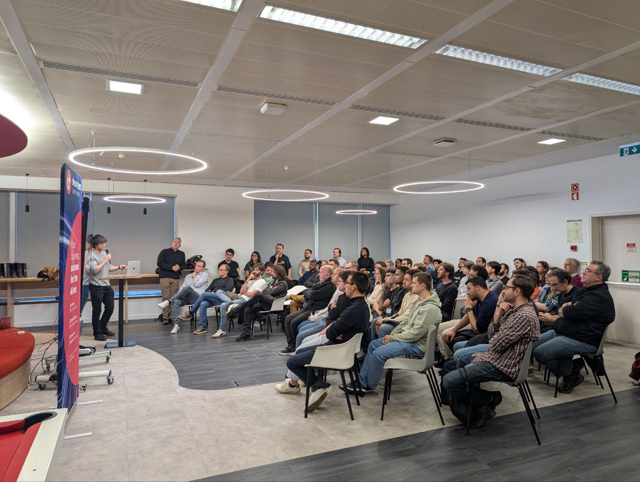 OWASP Lisboa #12 A large, engaged audience of cybersecurity professionals seated in the Devoteam office, listening to a presentation during the OWASP Lisboa event.