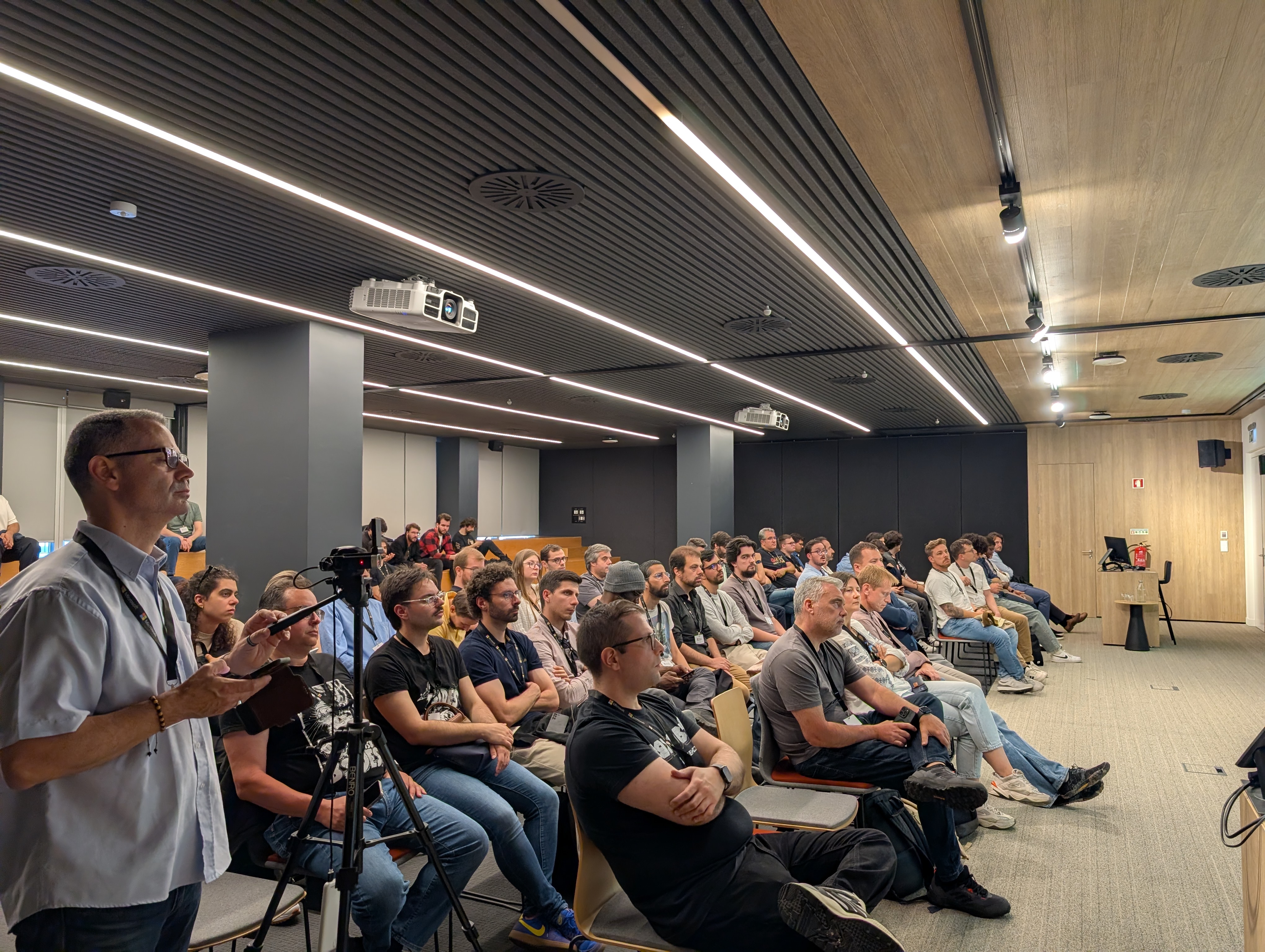 OWASP Lisboa #13 Side-angle view of a large, focused crowd of cybersecurity professionals sitting in an auditorium during an AppSec presentation.
